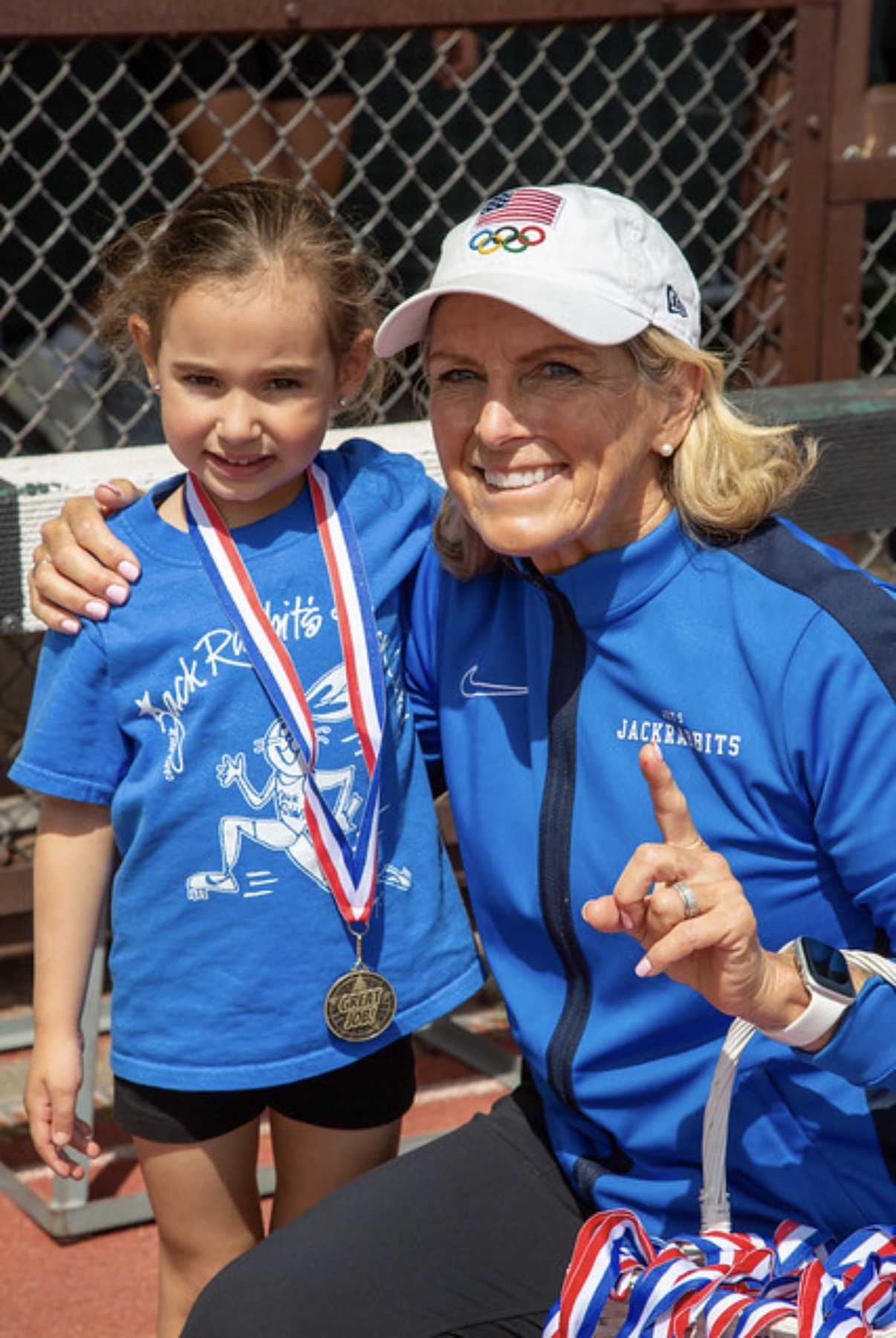 Joy in her Jackrabbits jacket with a young runner proudly wearing her medal at the Stanford Invitational